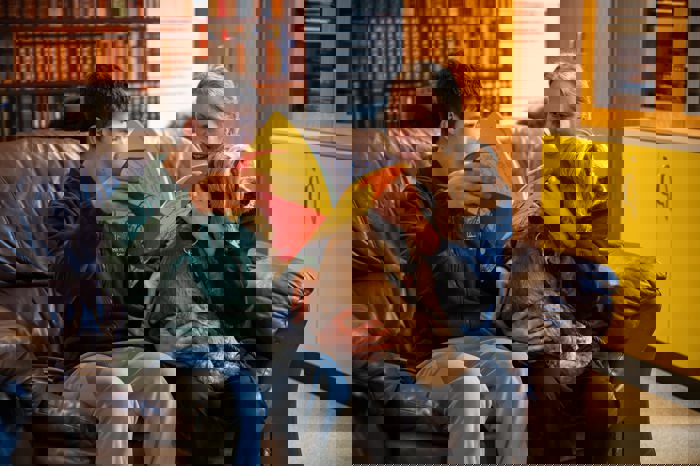 Reading a book on a sofa with a dog.