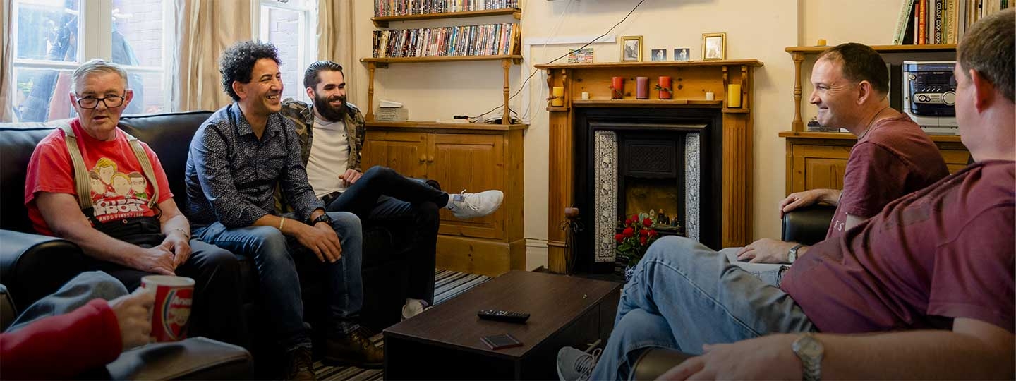 a small group sat in a front room chatting and laughing.