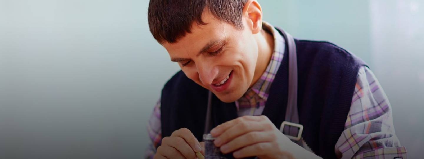 young man smiling whilst making pottery.