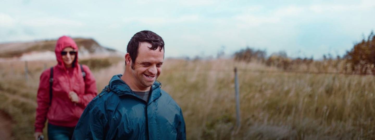 man smiling out walking in the countryside with his carer