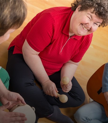 woman sat on floor with musical instruments smiling at camera.
