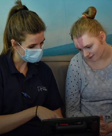 girl and carer looking at tablet.
