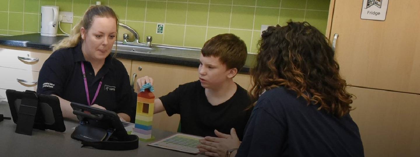 two carers and a boy sat at a table
