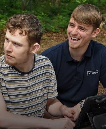 young lad and carer outside laughing.