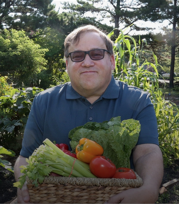 many smiling holding a box of vegetables. 