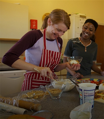 two women happily cooking in the kitchen.