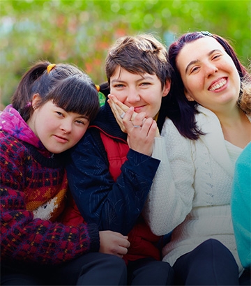three women sat together smiling at the camera.