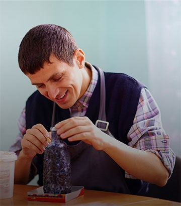 young man happily making pottery at the table.
