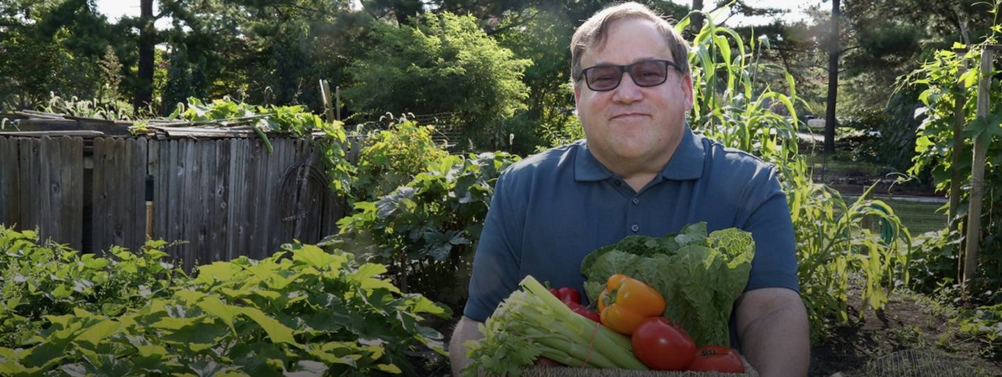 man smiling holding a box of vegetables.