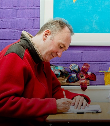 man sat at table doing some work.