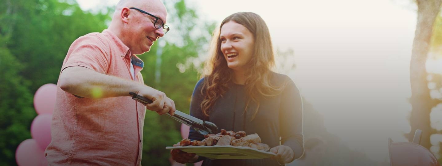 man and woman smiling at a barbeque.