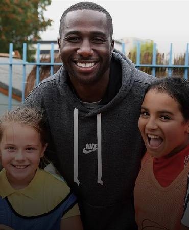  a coach and two children playing sports and smiling.