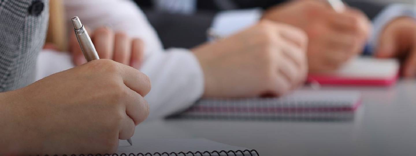 close up of hands writing in notebooks.