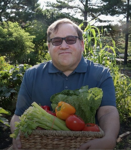  many smiling holding a box of vegetables.